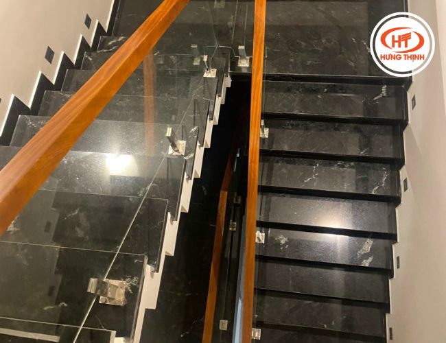 Cầu thang đá đen Granite Via Lactea phối lan can kính sang trọng.