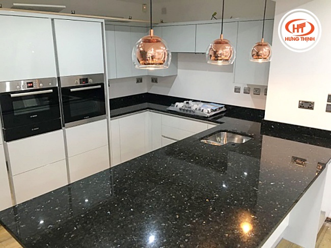 Mặt bàn sử dụng đá tự nhiên ốp bếp hiện đại nổi bật dưới hệ thống đèn chiếu sáng