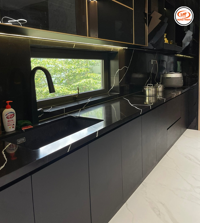 Gia chủ đồng bộ màu sắc của hệ tủ và màu đá bàn bếp đen