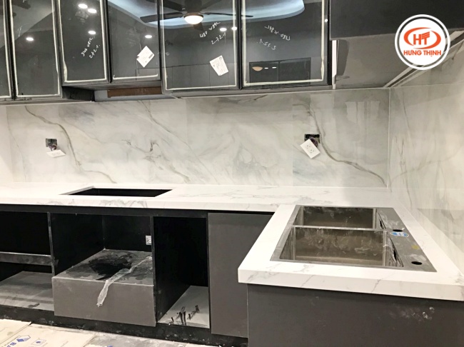 Mặt bàn bếp kết hợp tường ốp cùng chất liệu đá nung kết tạo tổng thể liền mạch