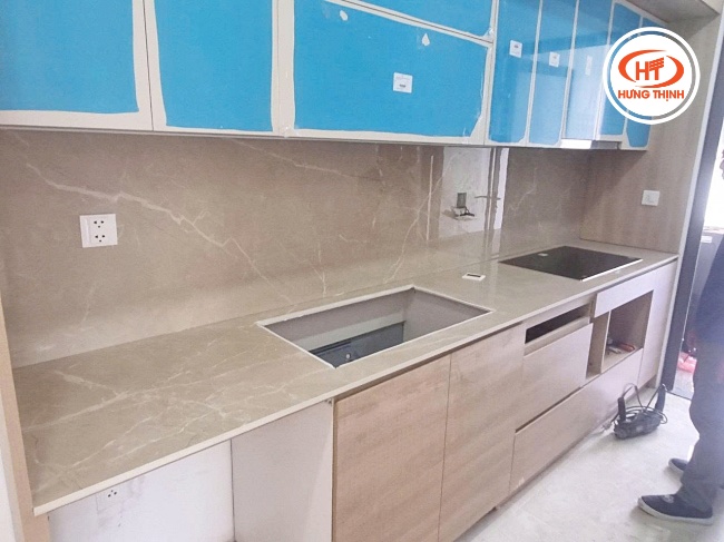 Mặt đá bếp màu be kết hợp với hệ tủ gỗ tạo cảm giác ấm cúng