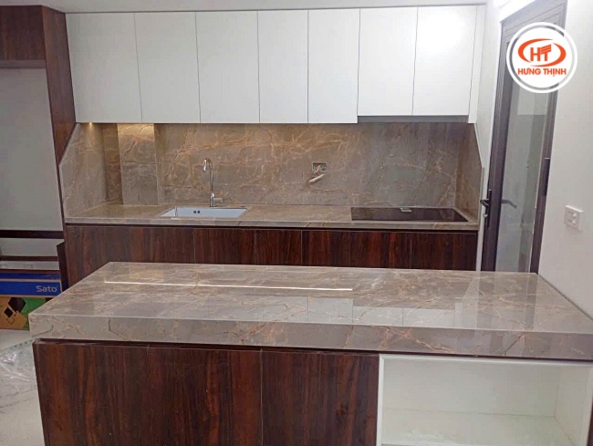 Bàn đảo bếp mặt đá màu nâu đất ấm áp mang lại cảm giác gần gũi, mộc mạc nhưng không kém phần sang trọng cho không gian bếp hiện đại